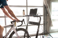 Rider using the Saris TD1 Trainer Desk — phone and tablet on desk surface