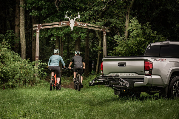 Cyclist loading a road bike onto the Saris SuperClamp G3 2-Bike Hitch Rack